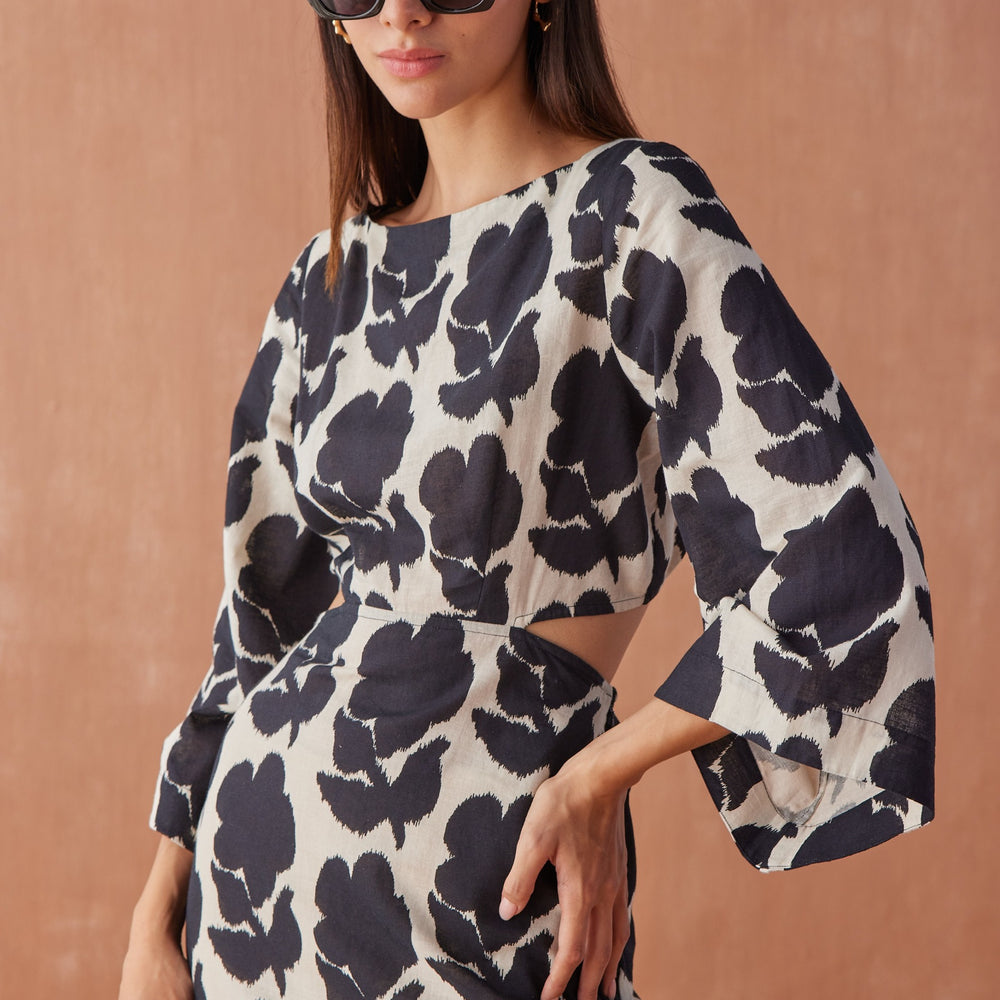 Front close-up of model wearing Peyton Midi in Emma Mussel, highlighting boat neckline, waist cut-out detail, and bold black floral print.