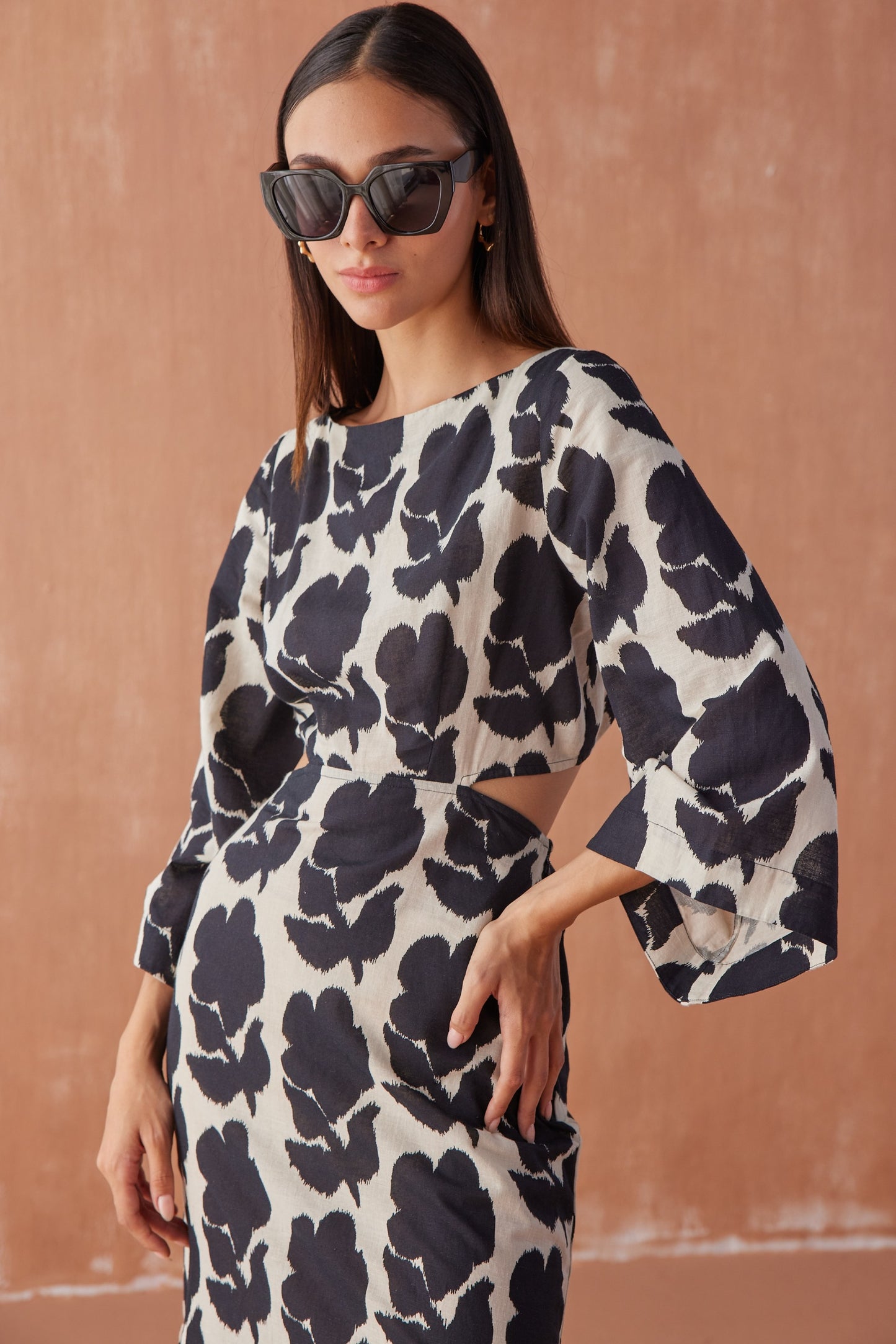 Front close-up of model wearing Peyton Midi in Emma Mussel, highlighting boat neckline, waist cut-out detail, and bold black floral print.
