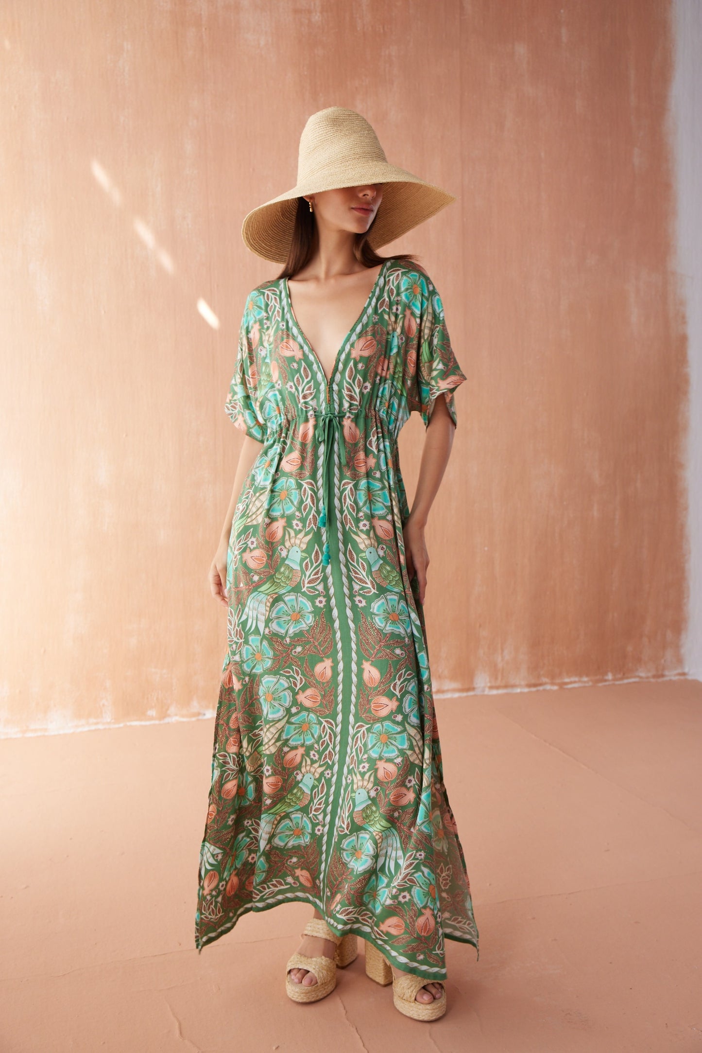 Front view of model wearing Pia Caftan in Kala Kelp, featuring deep V-neckline, flowing silhouette, and tropical floral print.