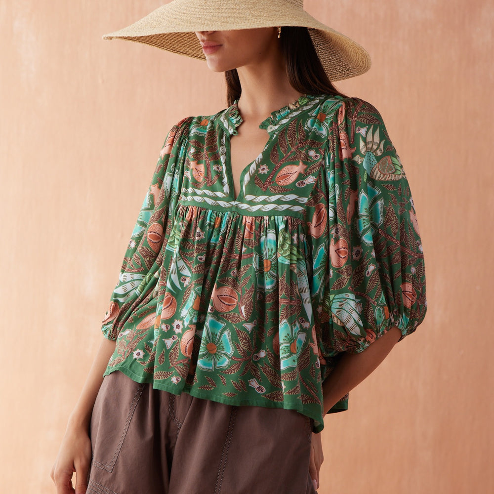 Front three-quarter view of model wearing the Nero Blouse in Emma, a button-front black blouse tucked into wide-leg black trousers.