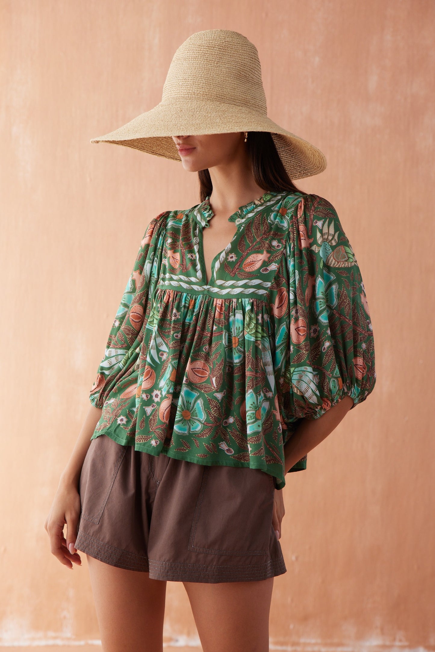 Front three-quarter view of model wearing the Nero Blouse in Emma, a button-front black blouse tucked into wide-leg black trousers.