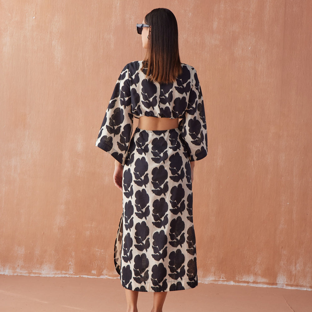 Back view of Peyton Midi in Emma Mussel, black floral linen midi dress with kimono sleeves, side cut-outs, and back slit.