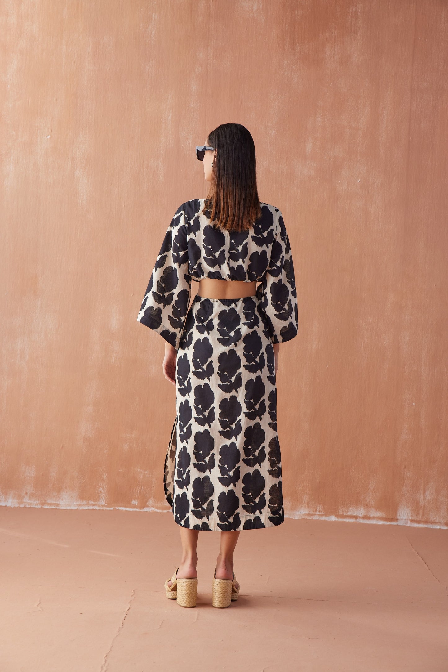 Back view of Peyton Midi in Emma Mussel, black floral linen midi dress with kimono sleeves, side cut-outs, and back slit.