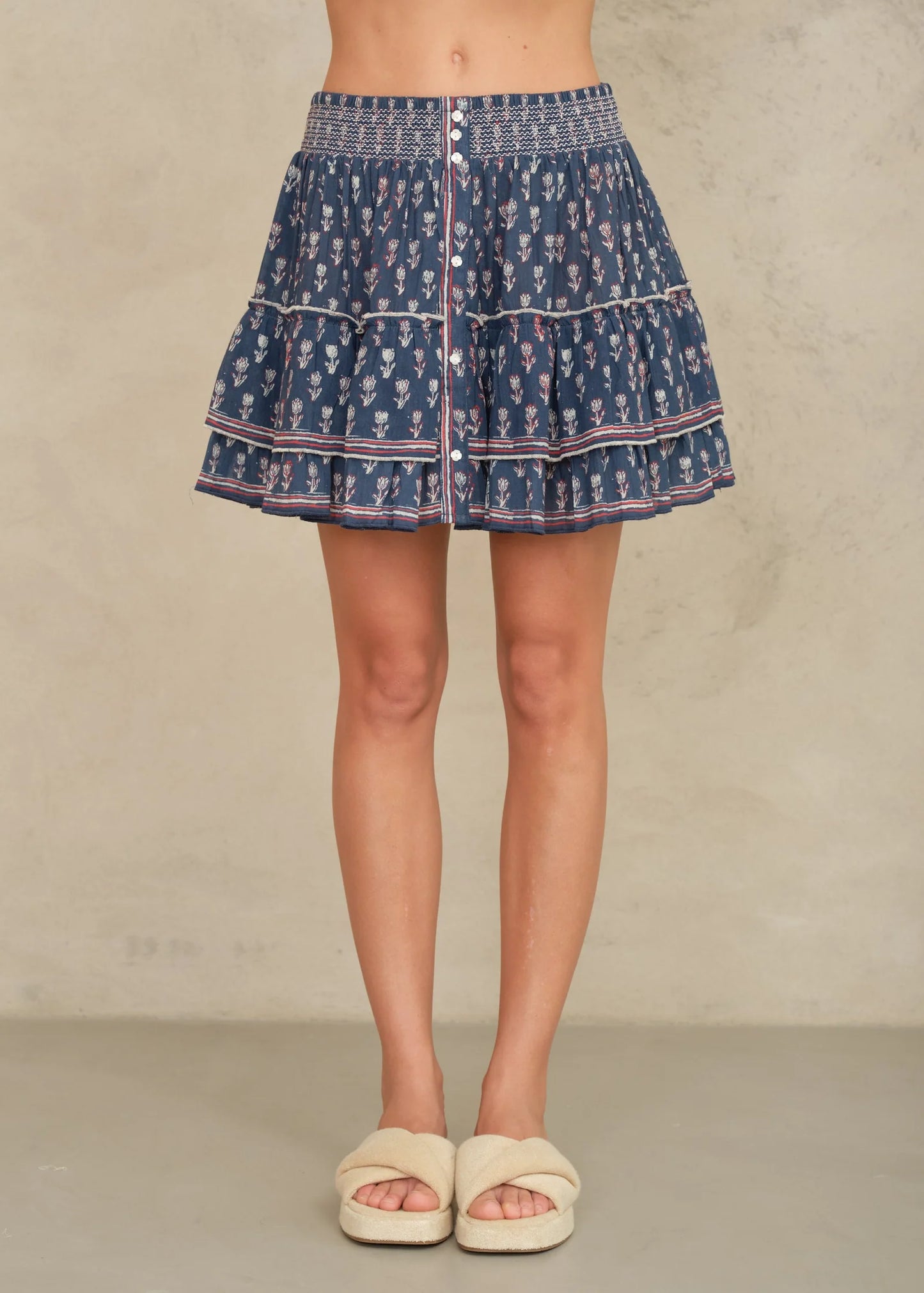 Person wearing a blue patterned skirt on a plain background