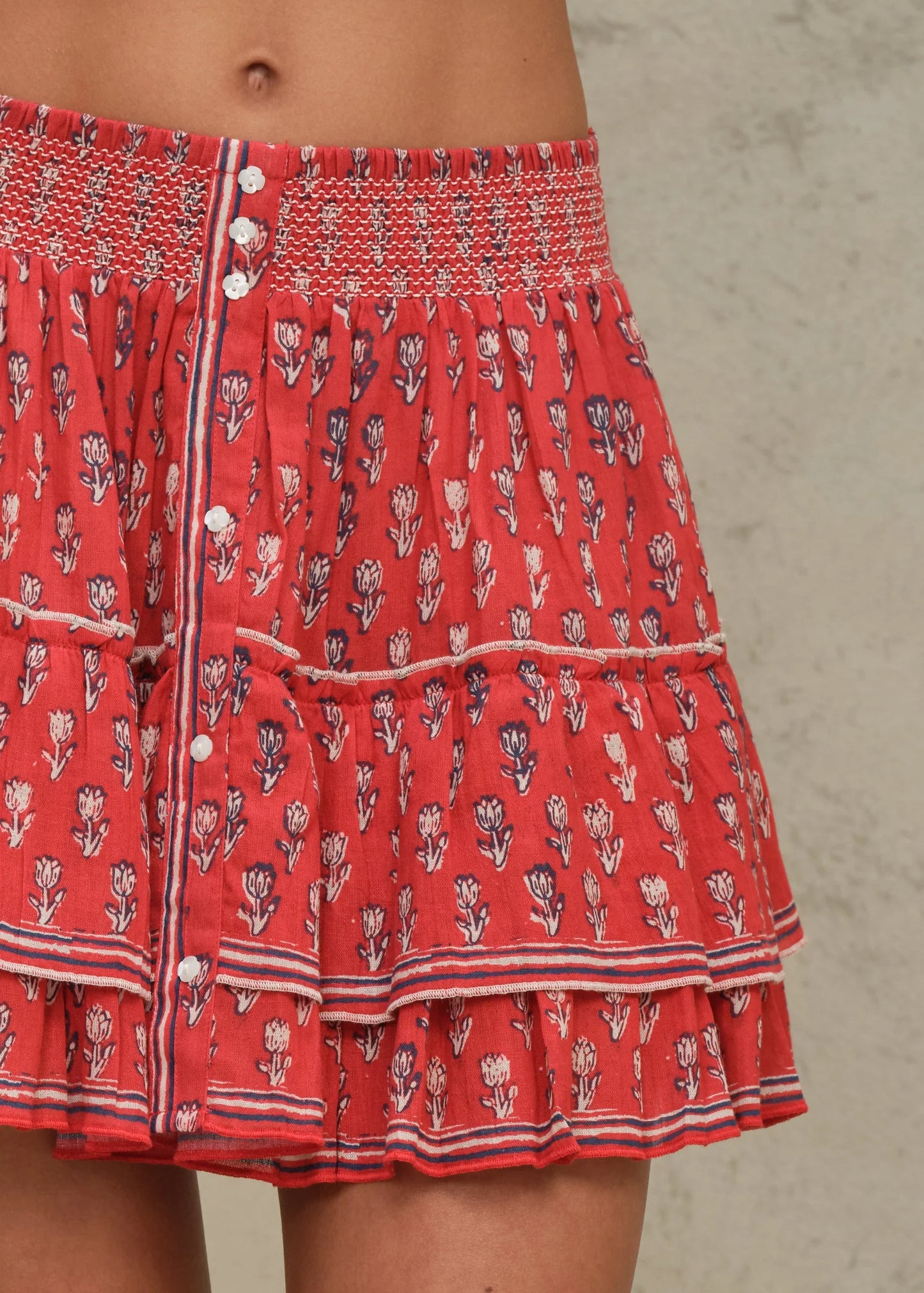 Red patterned shorts with white buttons on a neutral background