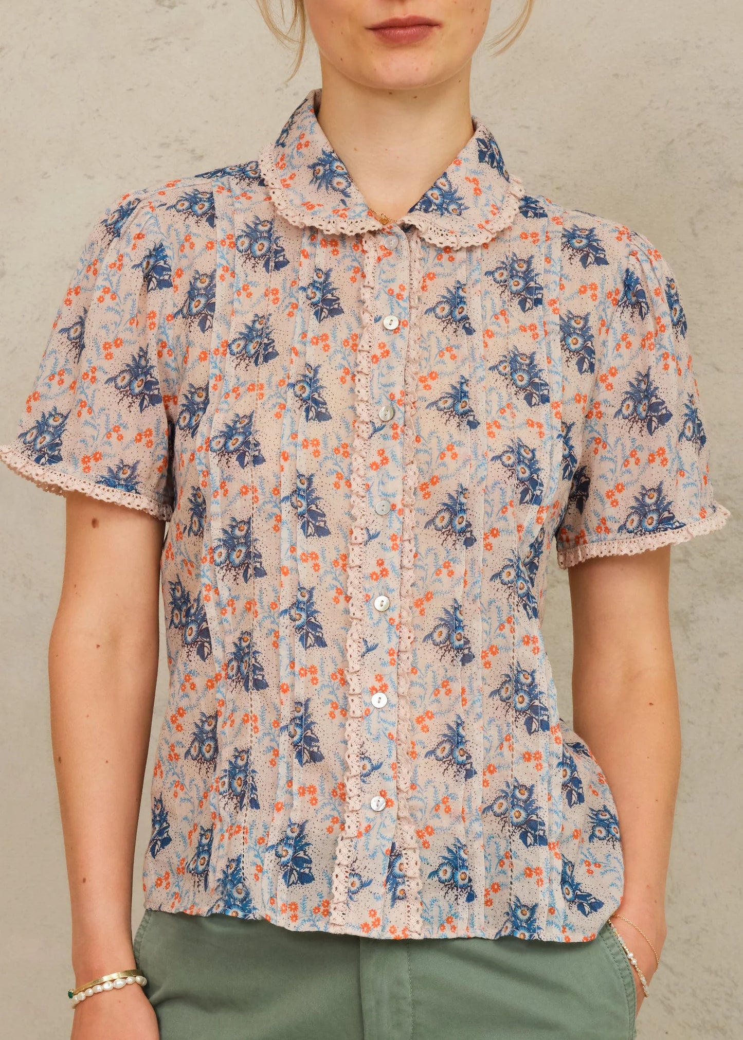 Person wearing a floral blouse with a neutral background