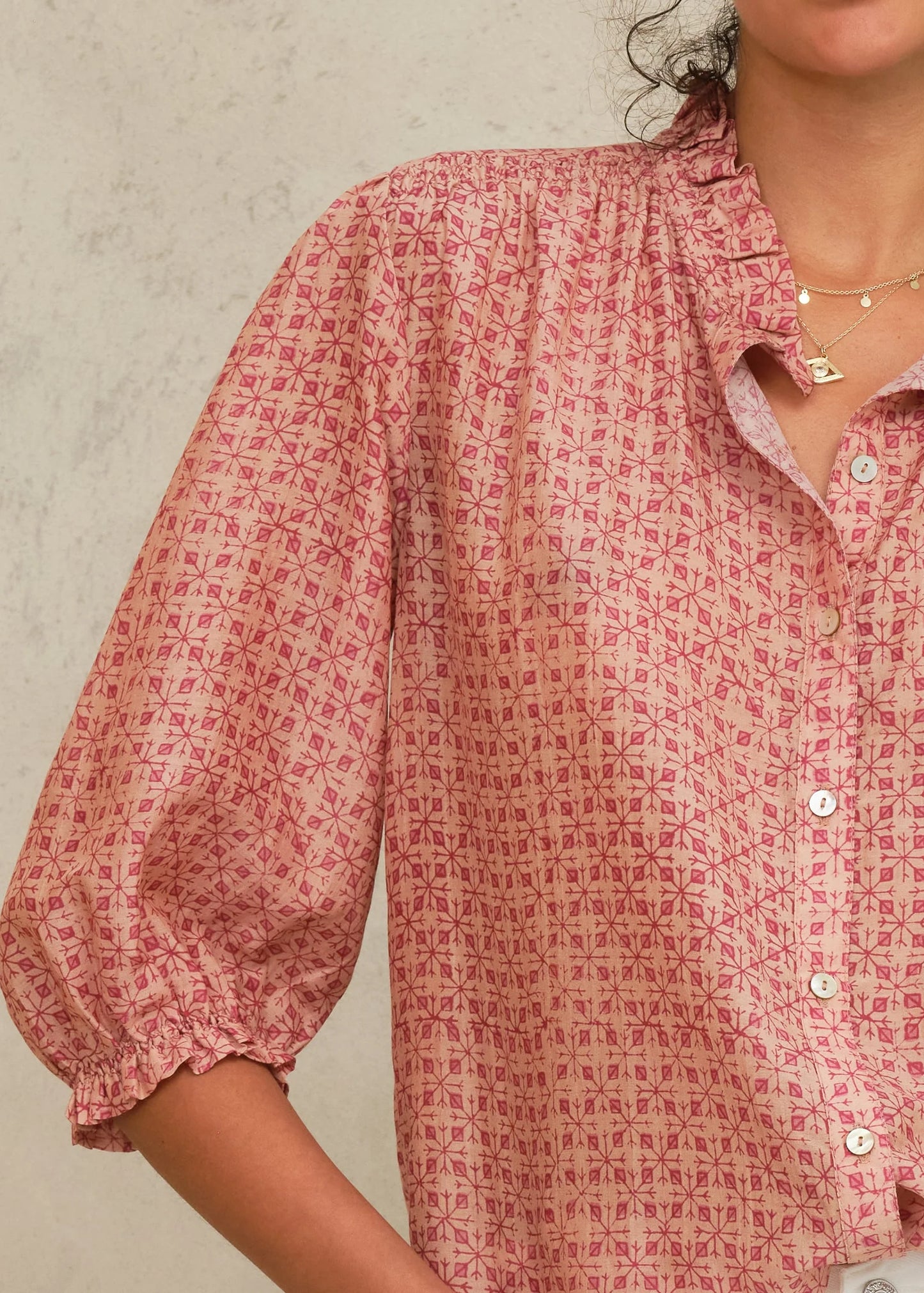 Person wearing a red patterned shirt against a neutral background