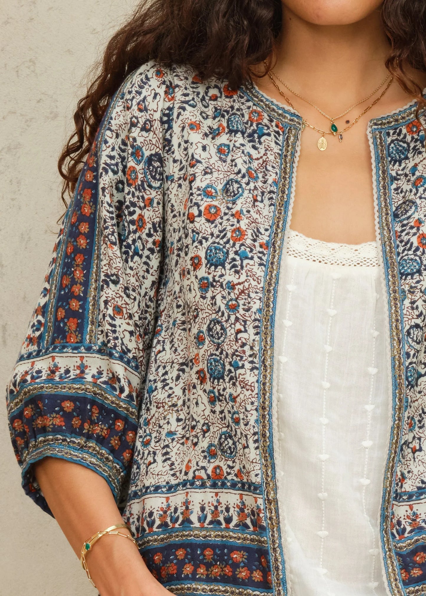 Woman wearing a patterned kimono over a white top against a neutral background