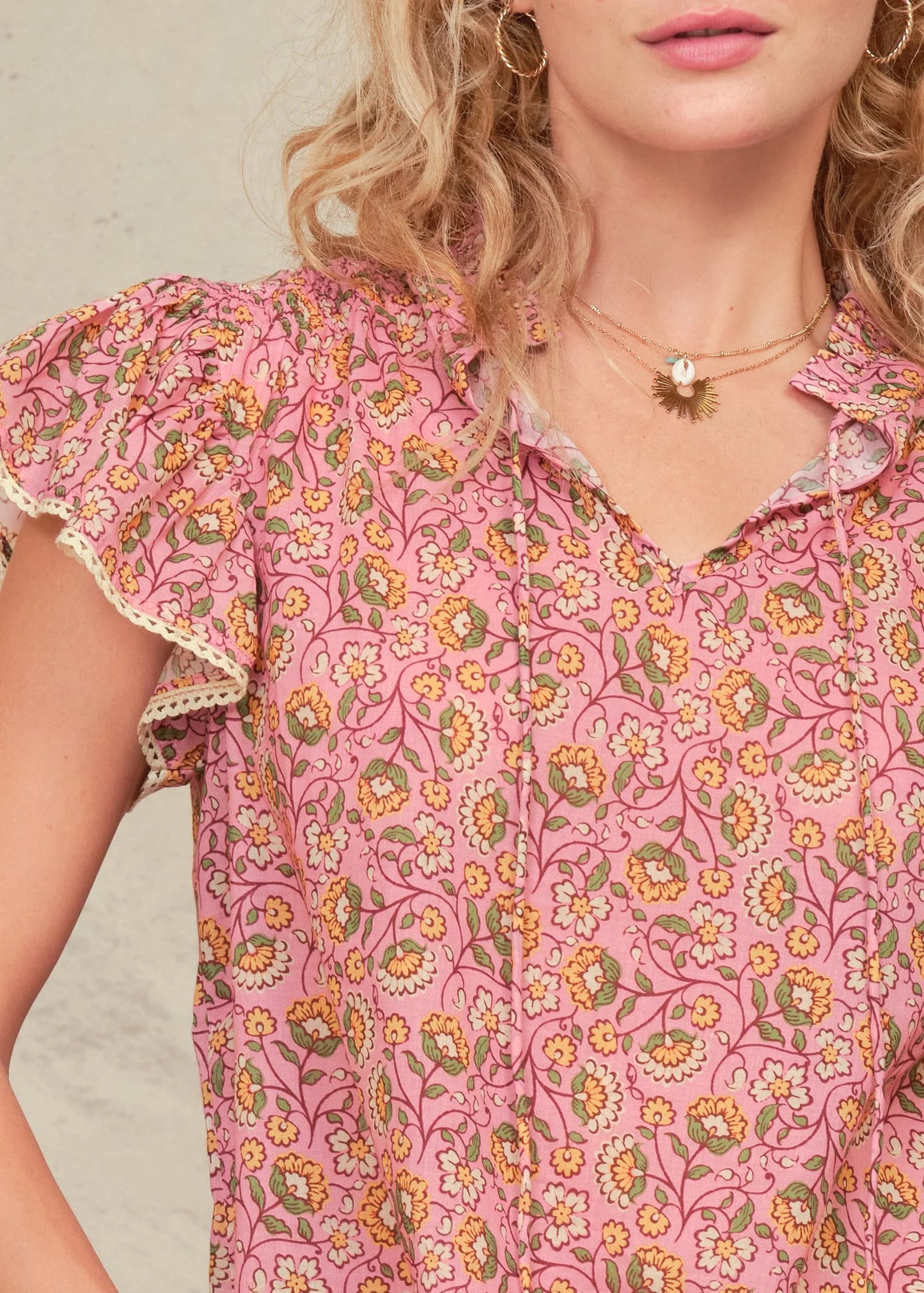 Woman wearing a pink floral blouse with a neutral background