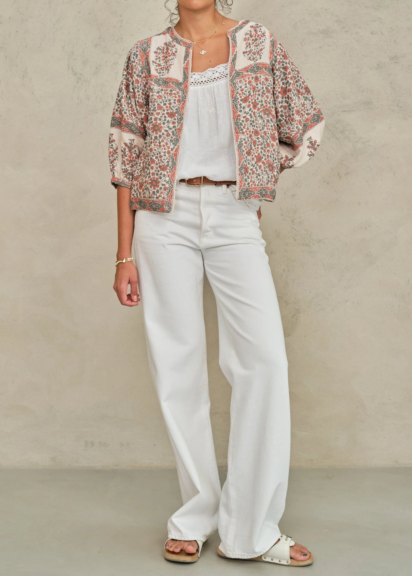 Woman wearing a floral jacket, white top, and pants against a neutral background