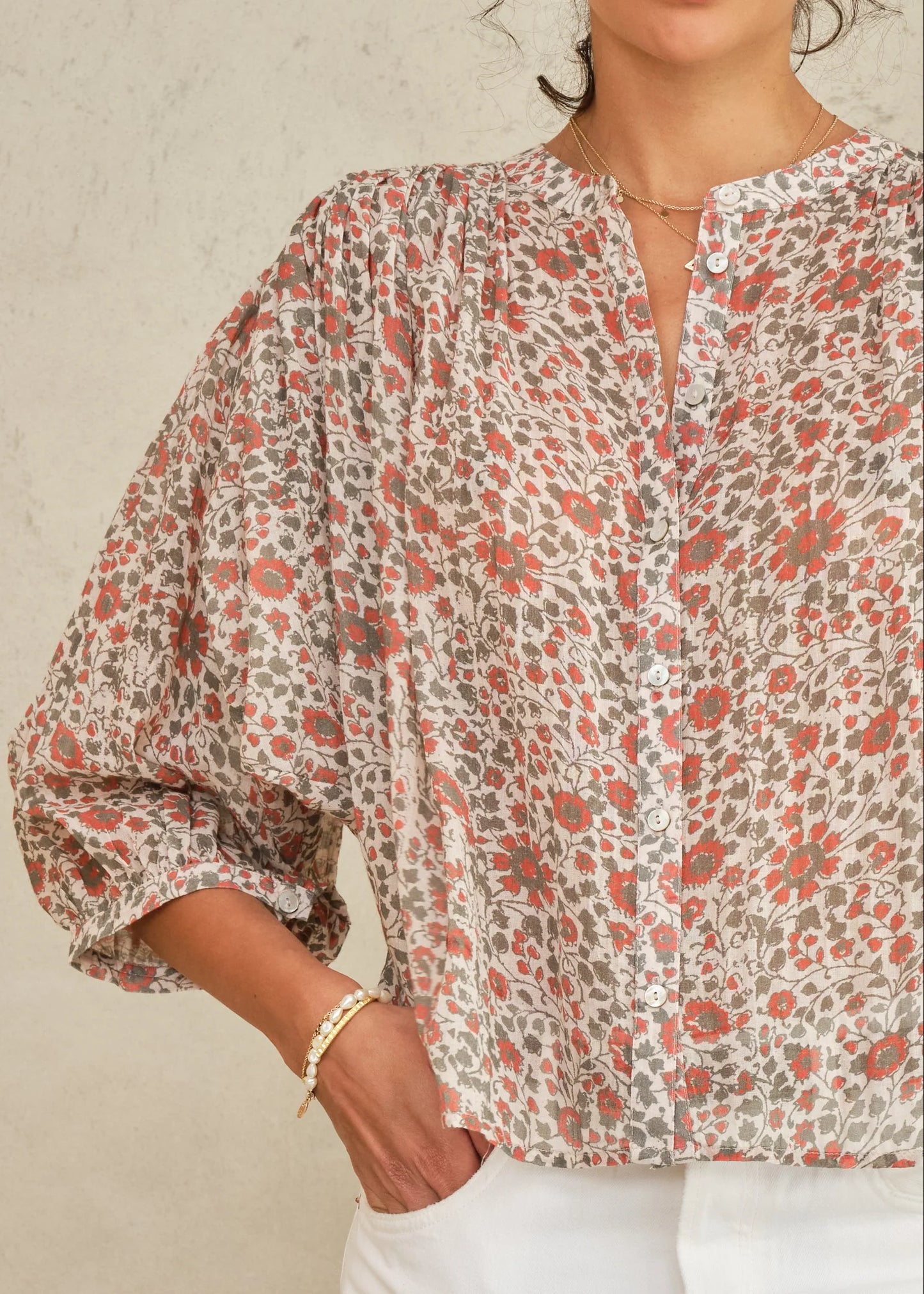 Woman wearing a floral blouse with a neutral background