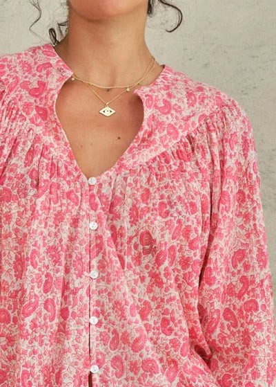 Close-up of a person wearing a pink floral blouse with a neutral background