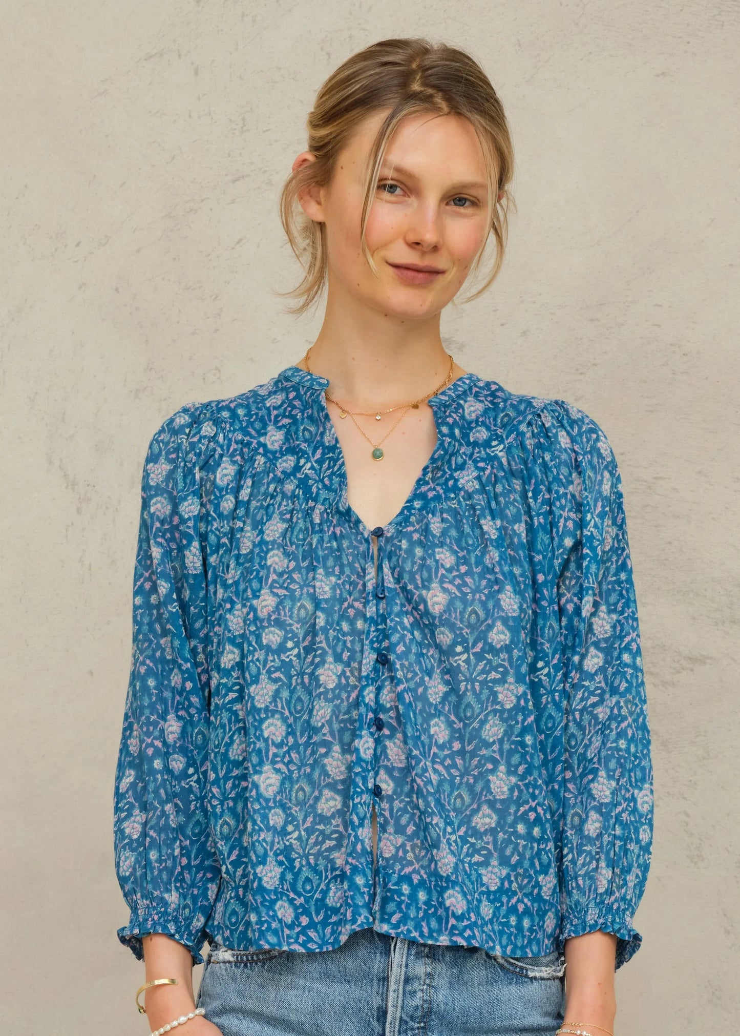 Woman wearing a blue floral blouse against a plain background