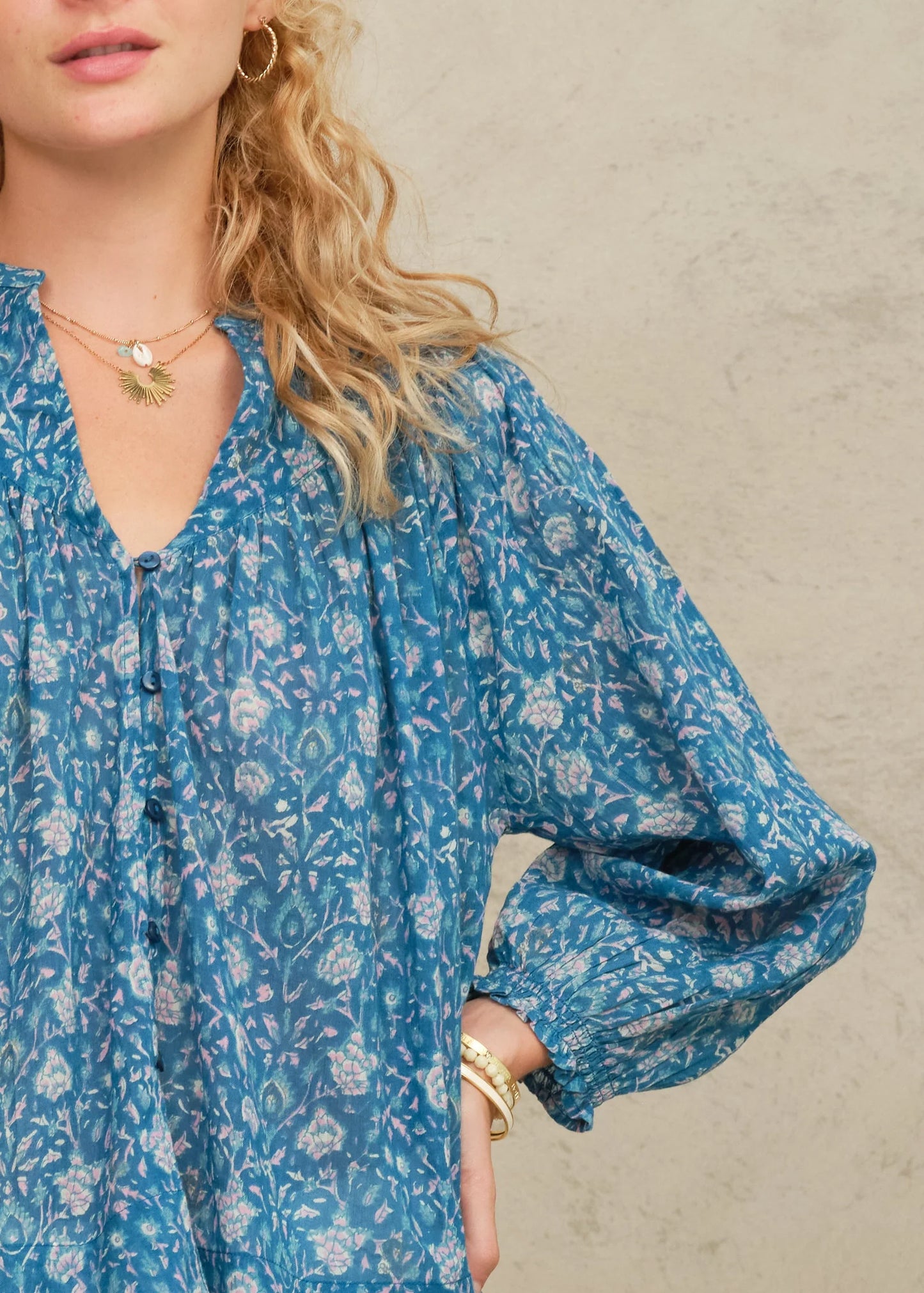Woman wearing a blue floral dress with a neutral background