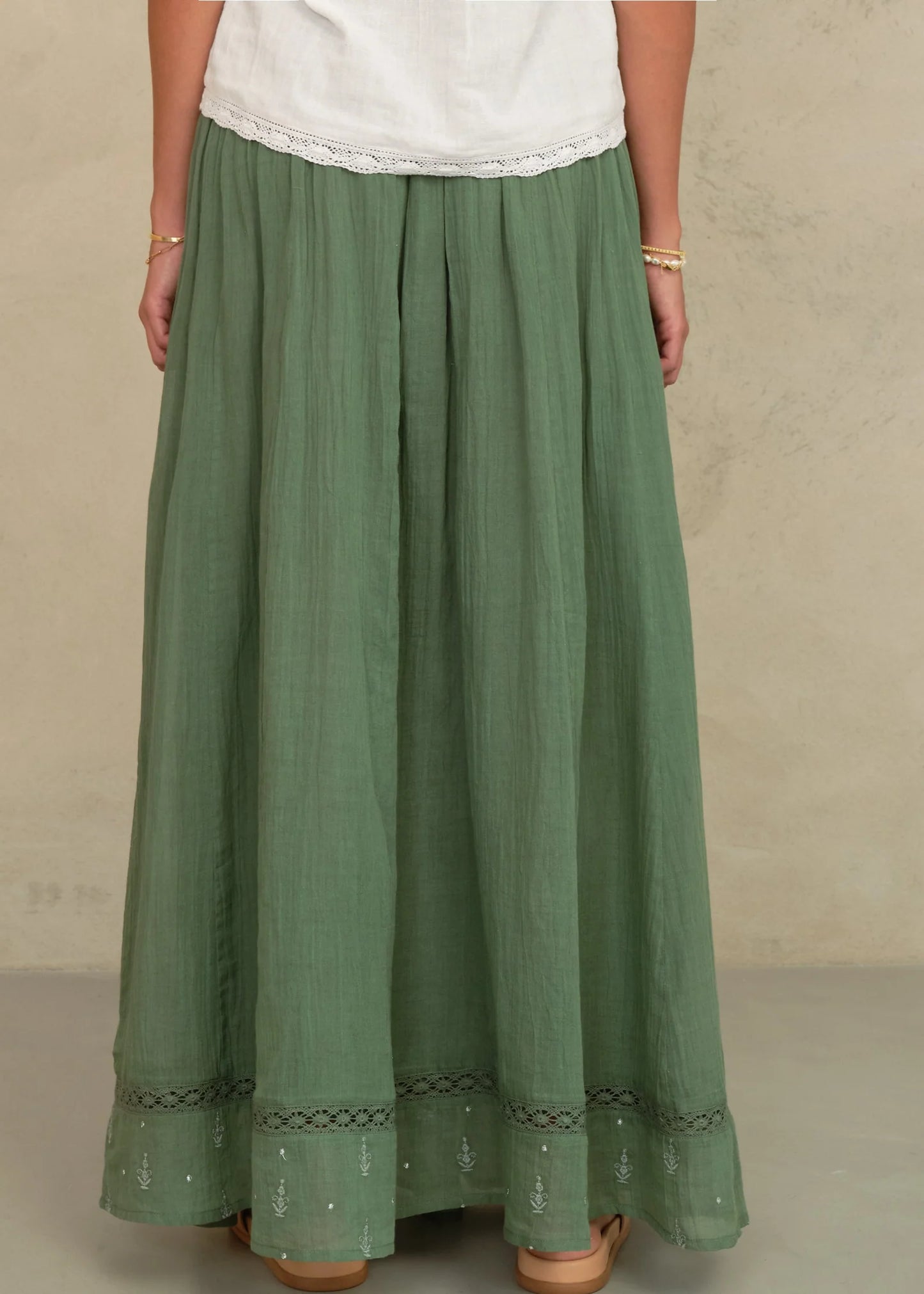 Green skirt worn by a person on a beige background