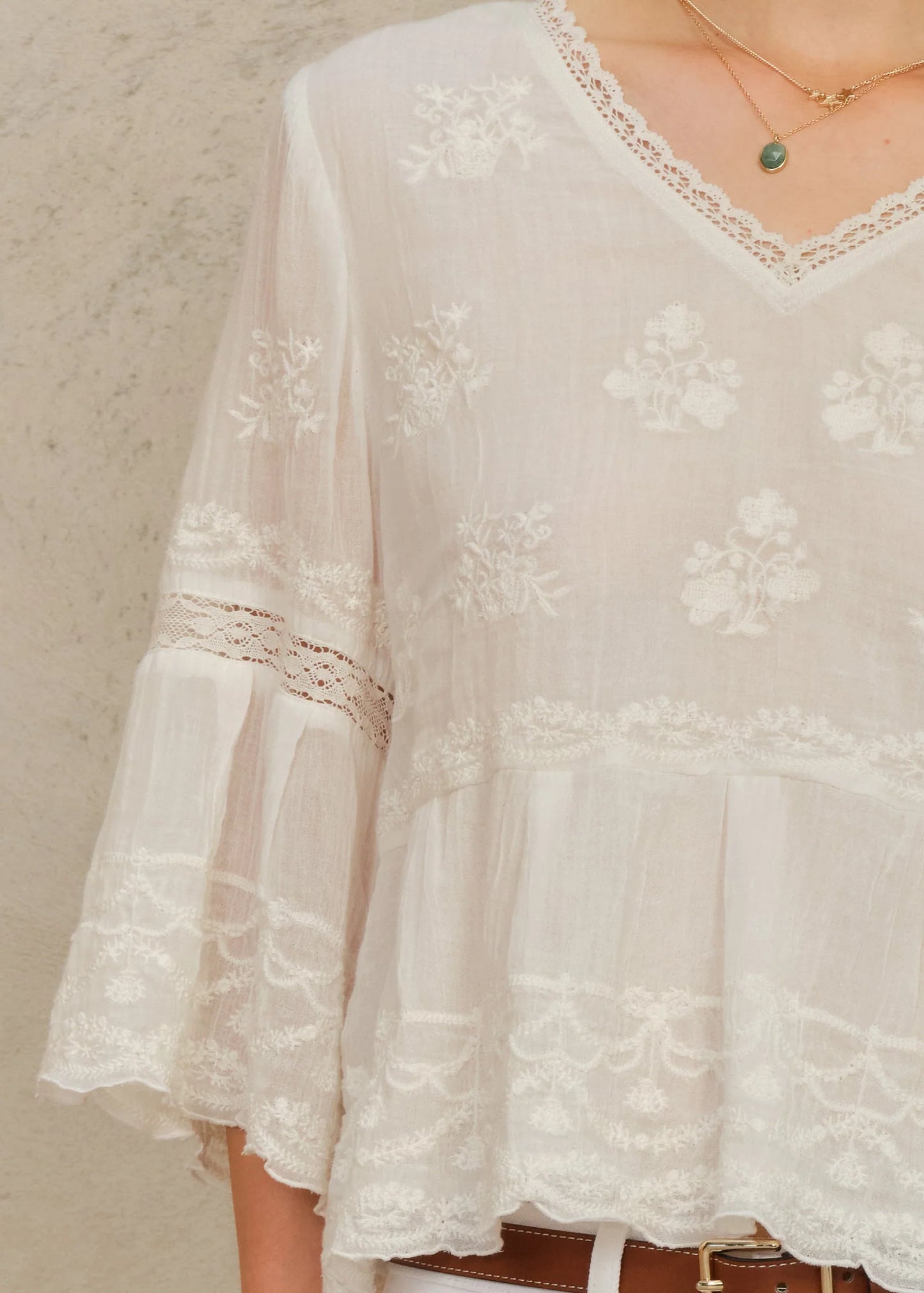 White lace blouse with long sleeves on a neutral background