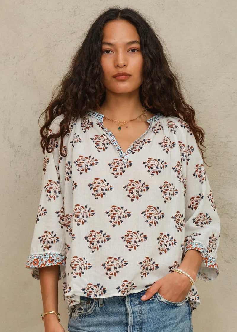 Woman wearing a floral blouse against a beige background